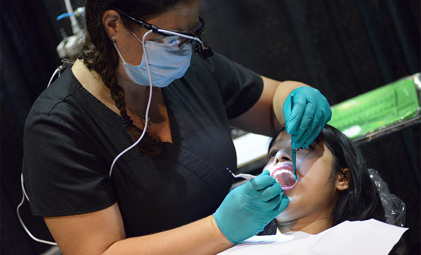 Dentist reviewing the teeth of a Latinx teen