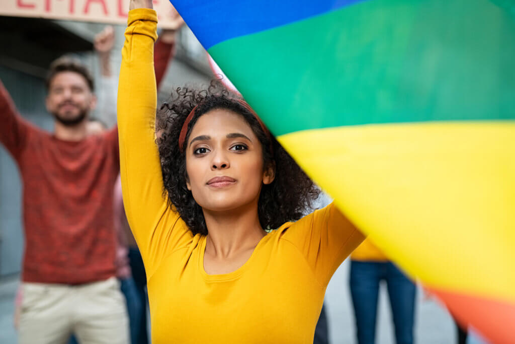 Young woman at women empowerment strike holding rainbow flag.