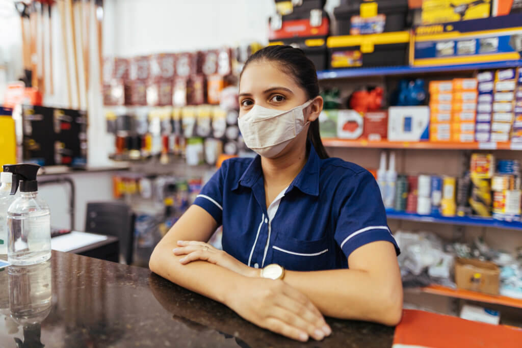 Young woman wearing face mask working in hardware store | Latina Equal Pay Day 2021